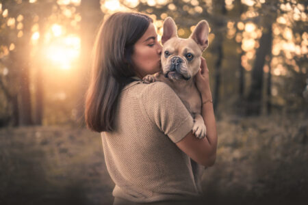 Frau küsst Französische Bulldogge; perfekter Moment für Hundefotograf oder Tiershooting.